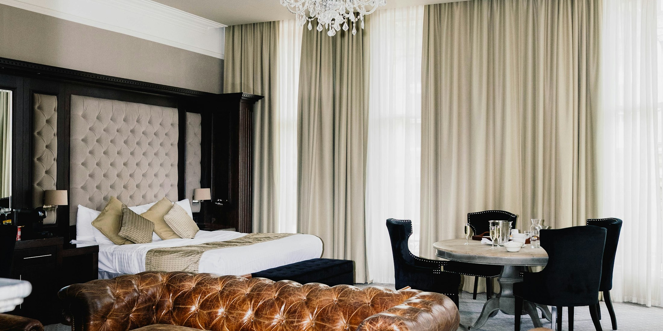 Light-filled luxury hotel suite — soft linens, draped curtains, classical luxury